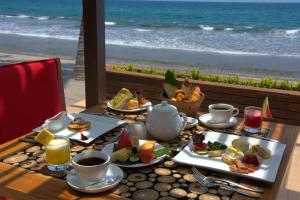 a table with plates of food and a view of the beach at The Chandi Boutique Resort & Spa in Senggigi
