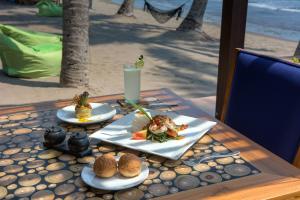 a table with plates of food and a drink on the beach at The Chandi Boutique Resort & Spa in Senggigi