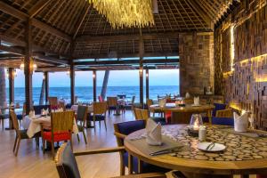a restaurant with tables and chairs and the ocean in the background at The Chandi Boutique Resort & Spa in Senggigi