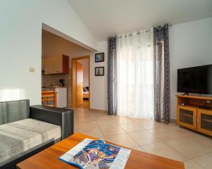 een woonkamer met een bank, een tv en een tafel bij Apartments Baresic in Medulin
