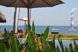 a view of the ocean from a resort with chairs and umbrellas at The Chandi Boutique Resort & Spa in Senggigi