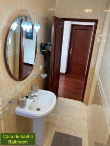 a bathroom with a sink and a mirror and a door at Villa Kethellen in Porto Covo