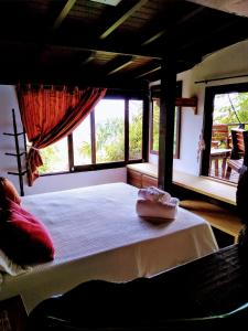 a bedroom with a large bed with a large window at La Roca Studio 7 in Praia do Rosa
