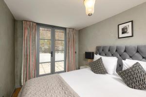 een slaapkamer met een groot bed en een raam bij PenthouseStays nr Notting Hill - Luxury 2 Bedroom King Bed Apartment - near Portobello Road in Londen