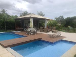 une terrasse à côté d'une piscine avec des chaises et un kiosque dans l'établissement Quintas de Sauipe, Casa F7, à Costa do Sauipe