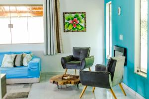 a living room with a blue couch and two chairs at Sítio com SPA, lareira e piscina - Piranguinho, MG in Piranguinho