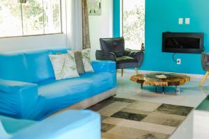 a blue living room with a blue couch and a table at Sítio com SPA, lareira e piscina - Piranguinho, MG in Piranguinho