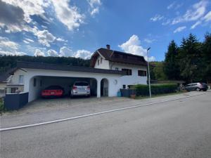ein weißes Gebäude mit zwei Autos in der Garage in der Unterkunft Apartment Feistriz in Rosental 9181 in Feistritz im Rosental