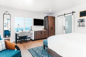 a bedroom with a bed and a desk with a tv at Del Mar Beach Hotel in San Diego