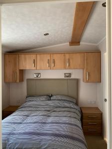 a bed in a small room with wooden cabinets at Immaculate 2-Bed Lodge in Monreith in Newton Stewart