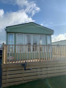 a small house on a deck with a fence at Immaculate 2-Bed Lodge in Monreith in Newton Stewart