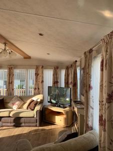 a living room with a couch and a tv at Immaculate 2-Bed Lodge in Monreith in Newton Stewart