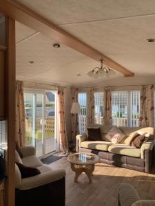 a living room with a couch and a table at Immaculate 2-Bed Lodge in Monreith in Newton Stewart