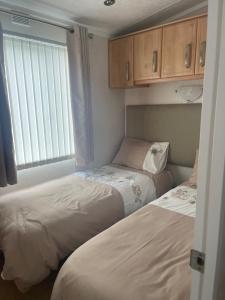 two beds in a small room with a window at Immaculate 2-Bed Lodge in Monreith in Newton Stewart