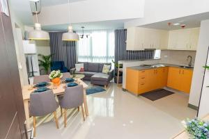 a kitchen and a living room with a table and chairs at Holiday suite at Uptown Parksuites II Uptown BGC in Manila