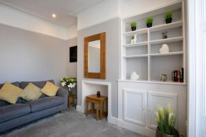 Spring Villa في ليستر: غرفة معيشة مع أريكة زرقاء ومرآة