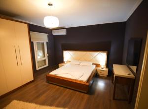 a bedroom with a bed and a black wall at Rooftop privé - your comfort apartment in Korçë