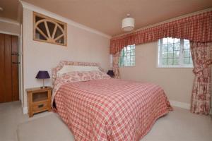 een slaapkamer met een bed met een rode deken en een raam bij Holmans NEW FOREST in Burley