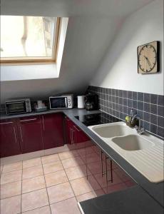 een keuken met een wastafel en een klok aan de muur bij Troisieme du nom in Nevers