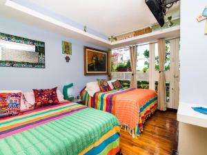 1 dormitorio con 2 camas y mantas coloridas en Casa ITZAE B&B- Lincoln Park dog friendly, en Ciudad de México