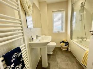 ein Badezimmer mit einem Waschbecken, einem WC und einer Badewanne in der Unterkunft Luxurious Beach House with spectacular sea views in Felixstowe