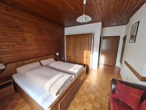 een slaapkamer met een bed en een houten muur bij Apartmenthaus Almwiese Flattnitz in Flattnitz