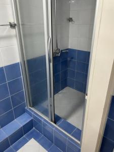 um chuveiro de azulejos azuis com uma porta de duche envidraçada em CITY CENTER DUPLEX em Belgrado