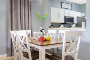 uma mesa de jantar com cadeiras brancas e uma cozinha em Moradda New Decor Vacation Home Regal Palms Resort em Davenport