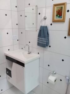 a white bathroom with a sink and a mirror at La Casa Rozada Prumirim in Ubatuba