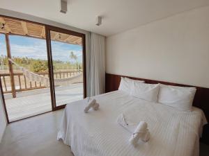 una camera da letto con un letto con lenzuola bianche e una grande finestra di Casa Seriguela - Praia do Patacho - Rota Ecológica dos Milagres a Pôrto de Pedras