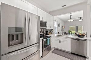 a kitchen with white cabinets and a stainless steel refrigerator at Newly Remodeled 4BD/4BA Townhouse-Regal Palms Resort Near Disney in Davenport