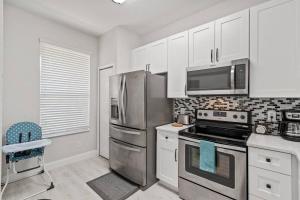 uma cozinha com um frigorífico de aço inoxidável e armários brancos em Newly Remodeled 4BD/4BA Townhouse-Regal Palms Resort Near Disney em Davenport