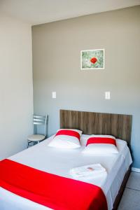 a bedroom with a large bed with red and white sheets at Hotel Palugi in Joinville