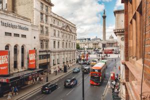 een drukke straat met auto's en een dubbeldekkerbus bij 2 Bedroom Apartment right on Trafalgar Square in Londen