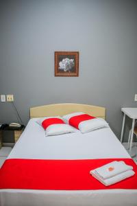 a bed with two red and white pillows on it at Hotel Palugi in Joinville