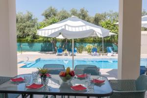 - une table avec un parasol à côté de la piscine dans l'établissement Rafaella Beach Villa- Pvt Pool-Near Sea/Beach, à Argaka