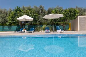 - une piscine avec deux parasols, des chaises, une table et des chaises dans l'établissement Rafaella Beach Villa- Pvt Pool-Near Sea/Beach, à Argaka