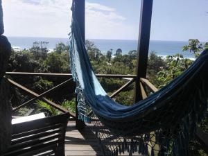 een hangmat op een terras met de oceaan op de achtergrond bij La Roca Studio 6 in Praia do Rosa