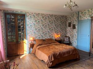 a bedroom with a large bed and floral wallpaper at Le Clos Chalmon Chambre d'hôte in Montignac