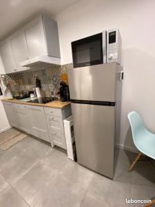 eine Küche mit einem Kühlschrank aus Edelstahl und einer Mikrowelle in der Unterkunft perle rare à la ciotat in La Ciotat