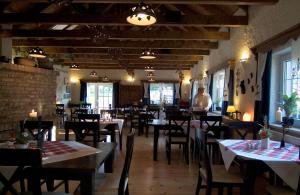 a restaurant with tables and chairs and a man standing in the background at Logis L Auberge Gutshof in Bischofswerda