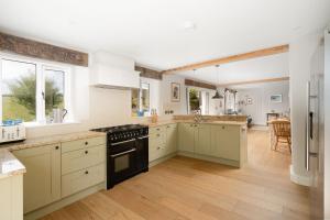 a large kitchen with white cabinets and black appliances at Daydreamer Cottage in Padstow