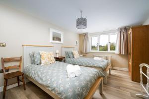 a bedroom with two beds and a chair at Daydreamer Cottage in Padstow
