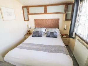 um quarto com uma grande cama branca e 2 almofadas em Poppy Lodge em Stratford-upon-Avon