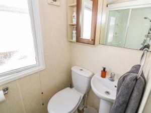 a bathroom with a toilet and a sink and a window at Poppy Lodge in Stratford-upon-Avon