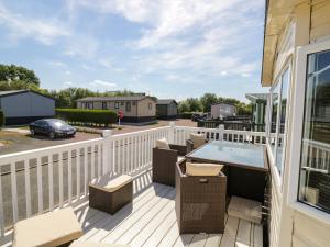 a deck with a hot tub and patio furniture at Poppy Lodge in Stratford-upon-Avon