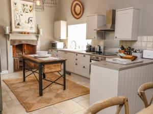 a kitchen with a table and a fireplace in it at The Compton Cottage in Cheltenham