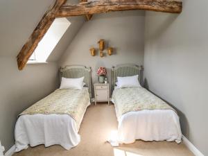 een zolderkamer met 2 bedden en een raam bij The Compton Cottage in Cheltenham
