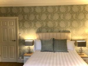 a bedroom with a bed with two lamps and a wall at White Gable in Scarborough