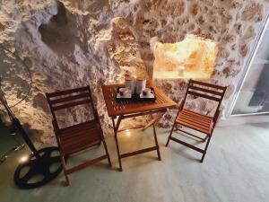 海若克利欧Anassa Cave by Estia的石墙间配有一张桌子和两把椅子